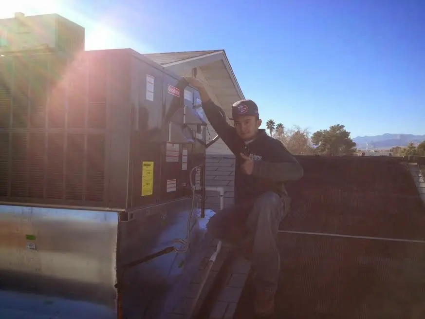 HVAC technician performing Air Duct Repair on a rooftop unit in Suffolk